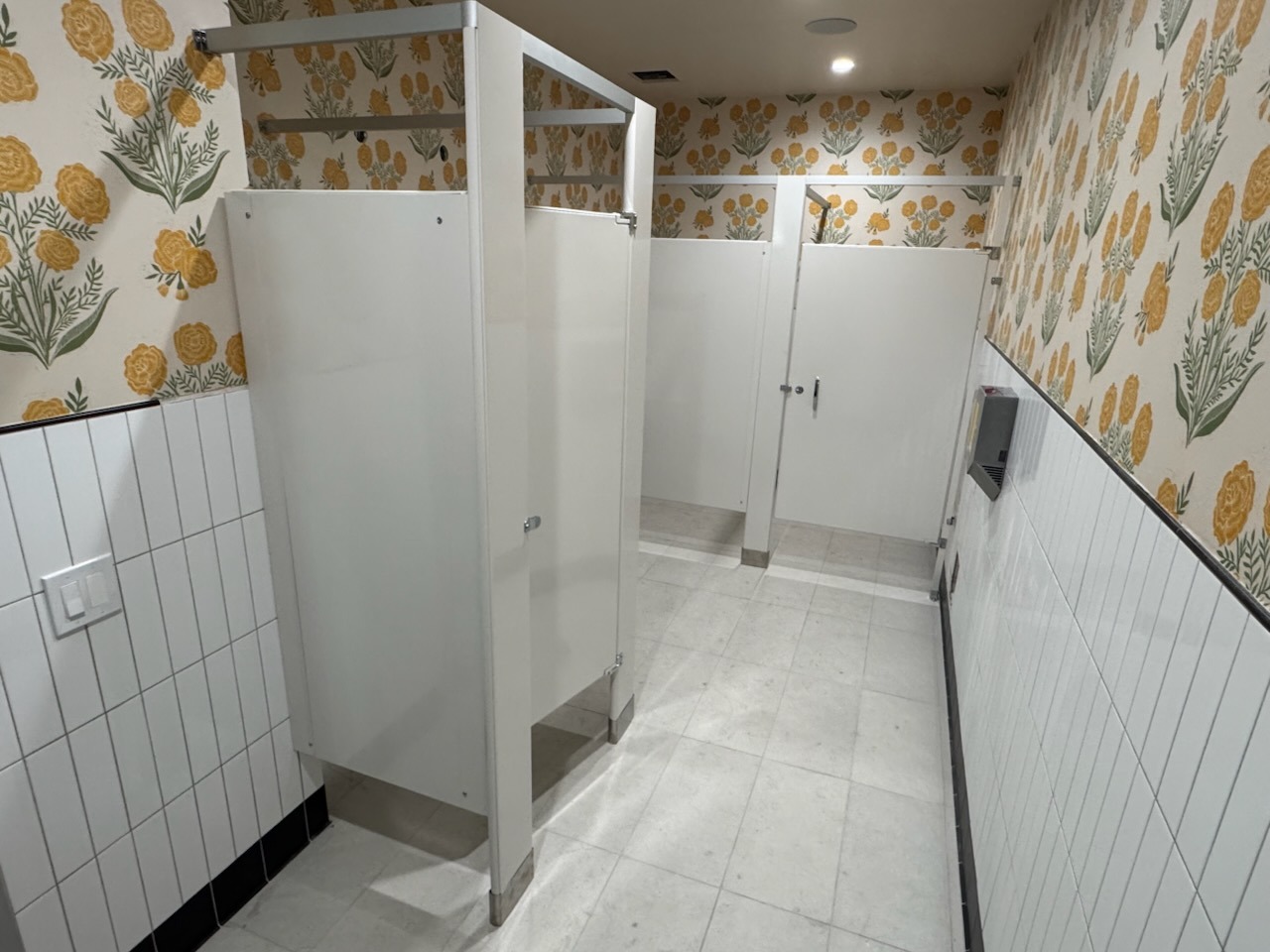 White powder coated steel bathroom stalls with floral wallpaper in Torrance, California